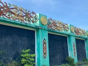Ukiran motif Dayak berwarna terpasang di dinding beton tugu perbatasan Pancasila