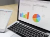Layar laptop menampilkan grafik dan bagan data di atas meja kerja