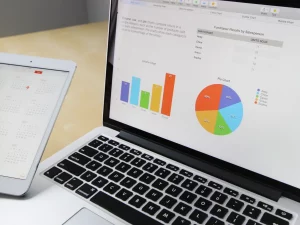 Layar laptop menampilkan grafik dan bagan data di atas meja kerja