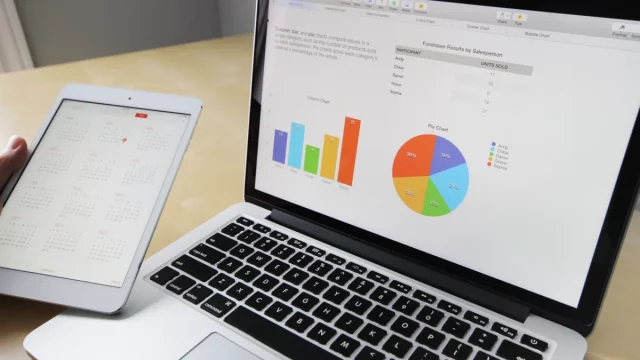 Layar laptop menampilkan grafik dan bagan data di atas meja kerja