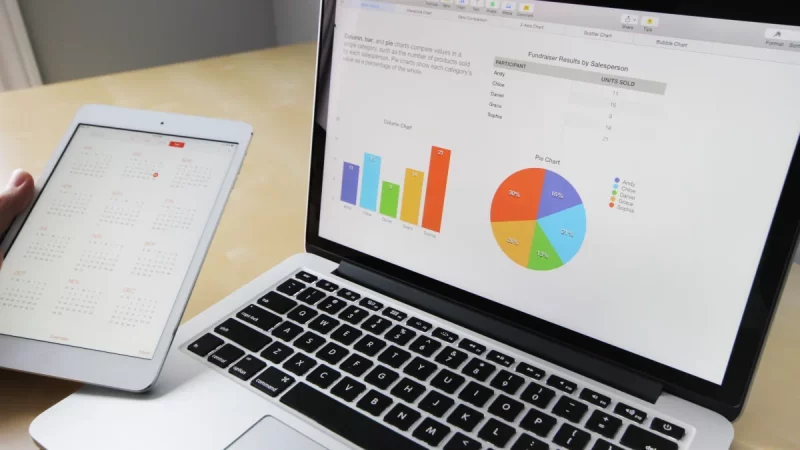 Layar laptop menampilkan grafik dan bagan data di atas meja kerja