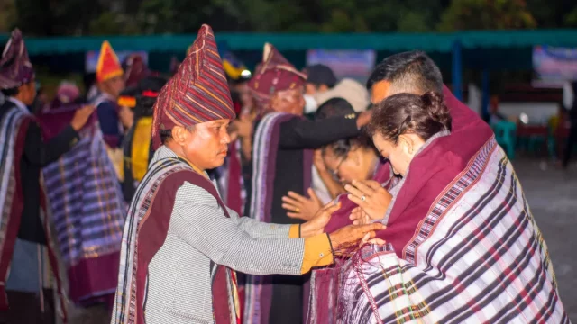 Tetua berulos menyampirkan ulos kepada pasangan dalam upacara mangulosi adat Batak Toba