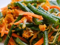 Urap kacang panjang, wortel, dan tauge berbalut kelapa parut berbumbu di atas piring putih