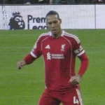Virgil van Dijk berlari mengenakan seragam merah Liverpool