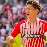 Penyerang Jepang SC Freiburg Yuito Suzuki memegang bola pertandingan seusai laga Bundesliga