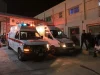 Dua ambulans dan kerumunan warga di depan rumah sakit militer pada malam hari di Karak