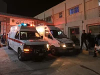 Dua ambulans dan kerumunan warga di depan rumah sakit militer pada malam hari di Karak