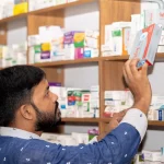 Ilustrasi seorang laki-laki mengambil kotak obat dari rak apotek di Bangladesh