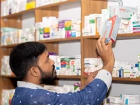 Ilustrasi seorang laki-laki mengambil kotak obat dari rak apotek di Bangladesh