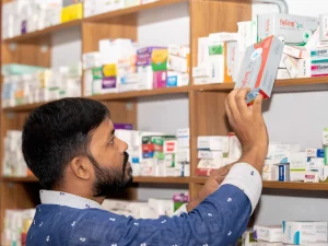 Ilustrasi seorang laki-laki mengambil kotak obat dari rak apotek di Bangladesh