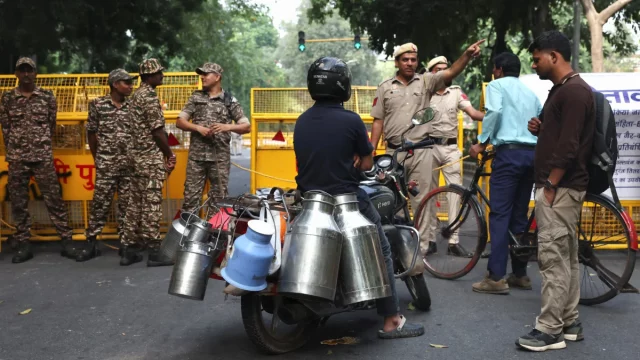Petugas keamanan di depan barikade kuning mengarahkan warga di New Delhi, India