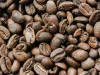 Hamparan biji kopi sangrai berwarna cokelat tua memenuhi seluruh bidang gambar