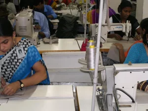 Ilustrasi buruh perempuan menjahit dengan mesin jahit industri di pabrik garmen di Bangladesh
