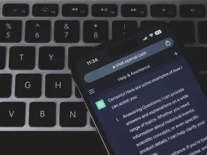 Ponsel menampilkan percakapan dengan chatbot AI di atas papan ketik