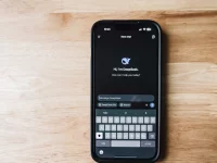 Ponsel di atas meja kayu menampilkan layar obrolan aplikasi kecerdasan buatan DeepSeek
