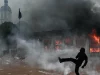 Demonstran menendang benda di tengah gas air mata di depan kantor pariwisata Lyon yang terbakar