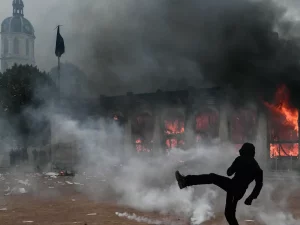 Demonstran menendang benda di tengah gas air mata di depan kantor pariwisata Lyon yang terbakar