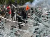 Demonstran antipemerintah terlihat dari balik kaca toko yang pecah di Tirana, Albania