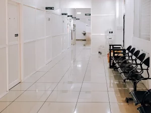 Ilustrasi lorong rumah sakit dengan deret kursi tunggu hitam yang kosong