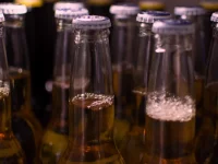 Ilustrasi deretan leher botol bir kaca bertutup logam tanpa label merek