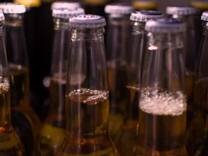 Ilustrasi deretan leher botol bir kaca bertutup logam tanpa label merek