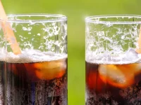 Ilustrasi dua gelas bening berisi minuman soda kola dengan es batu dan sedotan