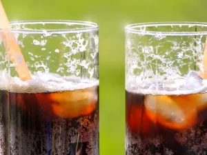 Ilustrasi dua gelas bening berisi minuman soda kola dengan es batu dan sedotan