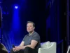 Elon Musk duduk di atas panggung dalam sebuah acara