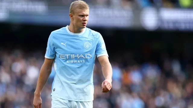 Erling Haaland berseragam biru muda Manchester City berjalan di lapangan