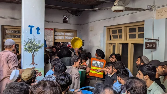 Warga dan petugas penyelamat berkerumun di lorong sekolah setelah atap runtuh di Peshawar