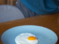 Ilustrasi butir garam ditabur ke telur mata sapi di piring biru