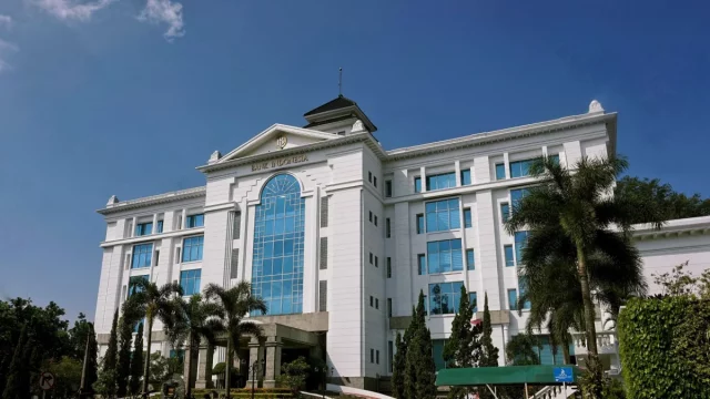 Gedung putih kantor Bank Indonesia di Bandung dengan deretan pohon palem di bawah langit biru