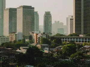 Deretan gedung perkantoran bertingkat Jakarta menjulang di atas permukiman padat berpohon