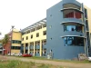 Ilustrasi gedung kampus Bishop Jerome Institute berwarna biru-kuning di Kollam, Kerala, India