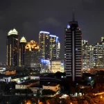 Ilustrasi gedung-gedung pencakar langit kawasan niaga SCBD yang menyala pada malam hari di Jakarta