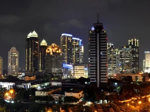 Ilustrasi gedung-gedung pencakar langit kawasan niaga SCBD yang menyala pada malam hari di Jakarta