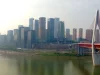 Gedung pencakar langit Chongqing berselimut kabut tipis di tepi sungai dengan jembatan gantung
