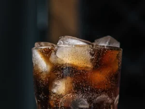 Ilustrasi segelas minuman soda cokelat berisi es batu dan gelembung