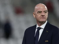 Presiden FIFA Gianni Infantino berjas gelap berdiri di pinggir lapangan stadion