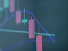 Grafik lilin harga saham bergerak turun pada layar monitor perdagangan