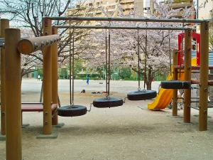 Ilustrasi ayunan ban dan perosotan di halaman taman kanak-kanak di Jepang saat sakura mekar