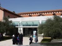 Halaman dalam kampus Damascus University, Suriah, dengan gedung beratap genting merah dan pohon zaitun