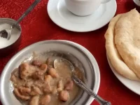 Ilustrasi sarapan ful, roti baladi, dan secangkir teh di sebuah meja di Kairo