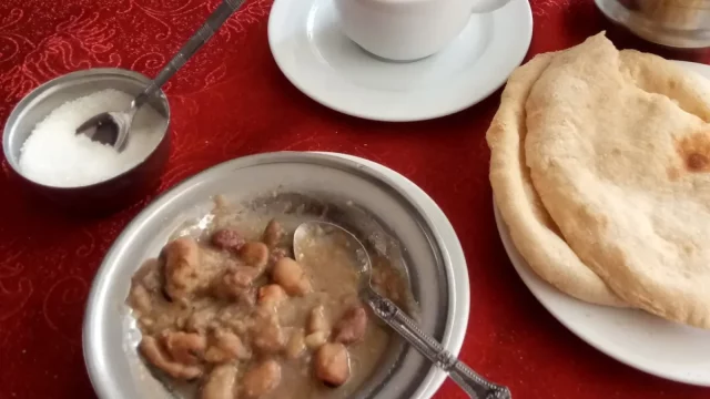 Ilustrasi sarapan ful, roti baladi, dan secangkir teh di sebuah meja di Kairo