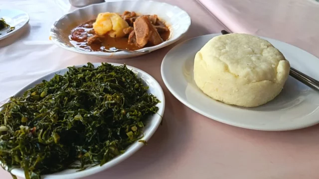 Ilustrasi sepiring ugali dengan sayur hijau dan semangkuk tumbukiza di Mombasa, Kenya