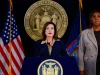 Gubernur New York Kathy Hochul berbicara di podium didampingi Letitia James