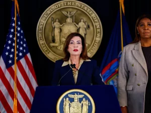 Gubernur New York Kathy Hochul berbicara di podium didampingi Letitia James