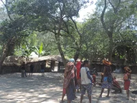 Warga dan pengunjung di halaman kampung suku Dani berlatar honai dekat Wamena, Lembah Baliem