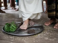 Ilustrasi kaki telanjang pengantin bergaun putih menginjak parang dan kapak di baki berisi daun