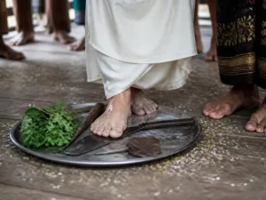 Ilustrasi kaki telanjang pengantin bergaun putih menginjak parang dan kapak di baki berisi daun